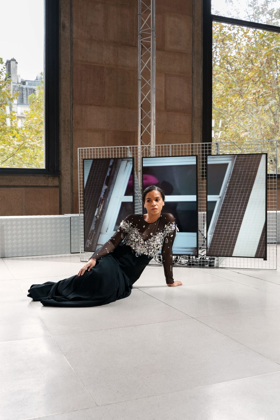 a person is lounging on the floor in a stylish form fitting black gown with floral embellishments on the upper part