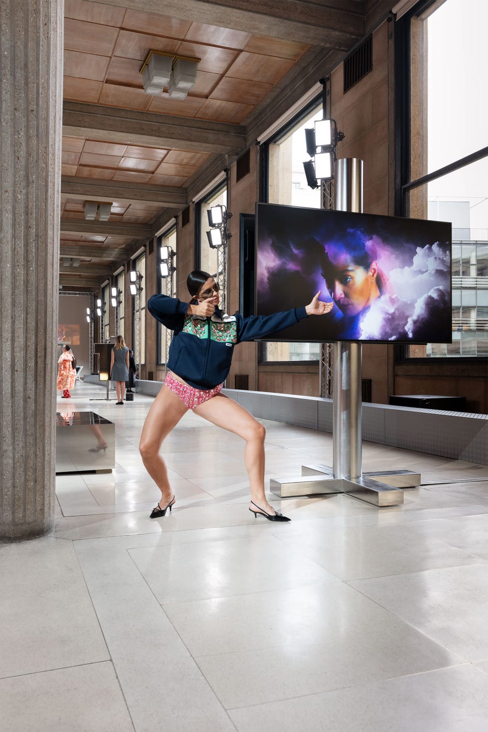 a model wearing a colorful jacket and patterned shorts stands in a dynamic pose showcasing a confident expression