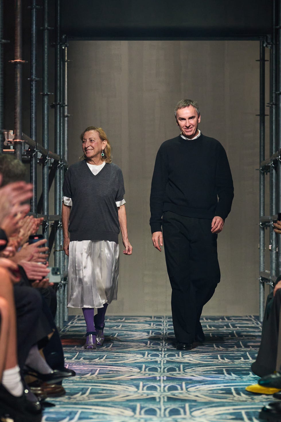 Two individuals walking on a runway during a fashion show