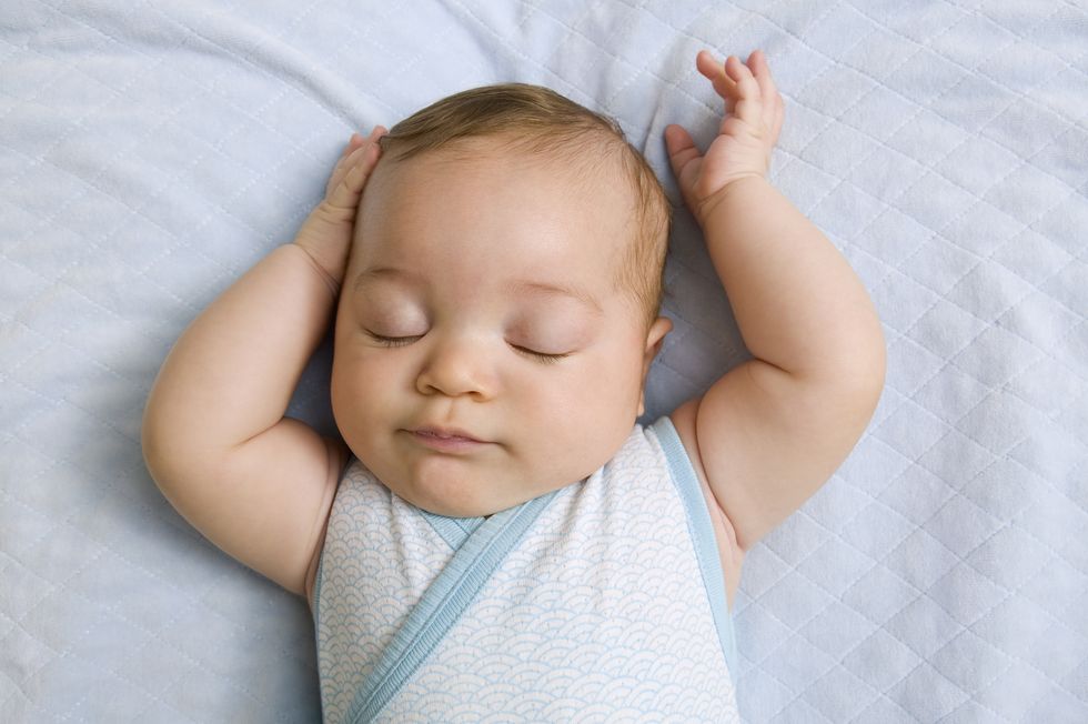 bebé durmiendo plácidamente con los brazos levantados