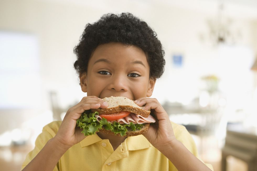 mixed race boy eating healthy sandwich