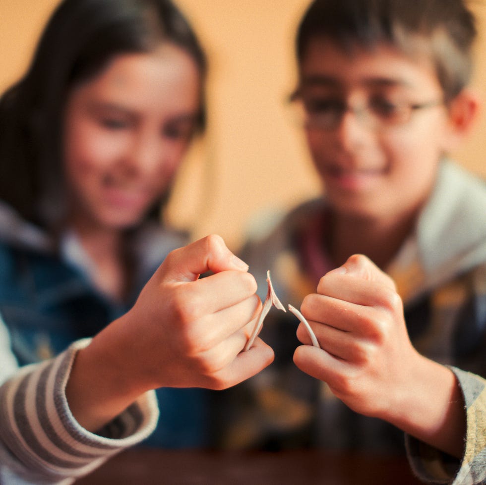 thanksgiving traditions - brother and sister snapping wishbone close up of two hands snapping a wishbone