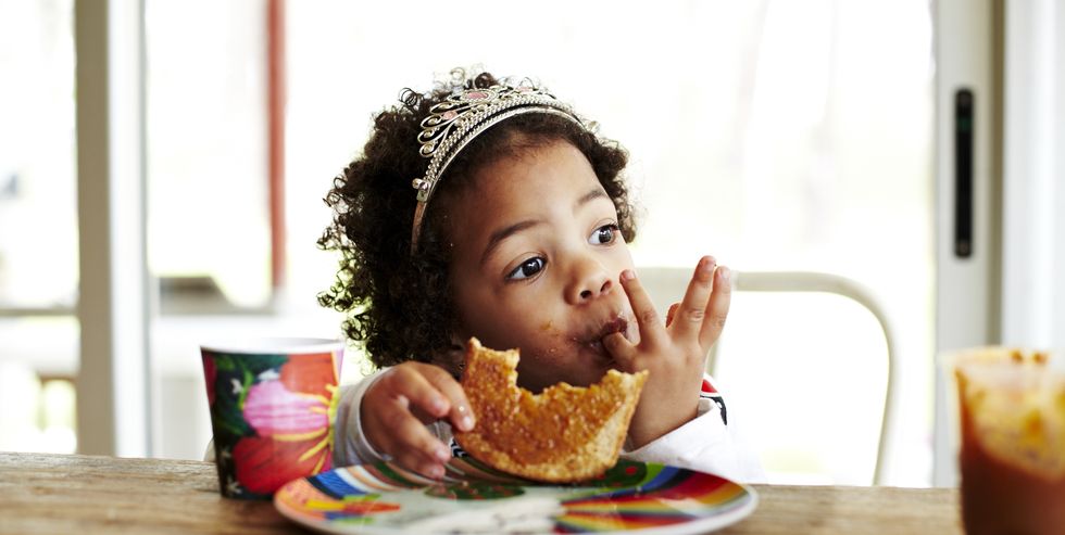 Mixed race girl eating lunch at table