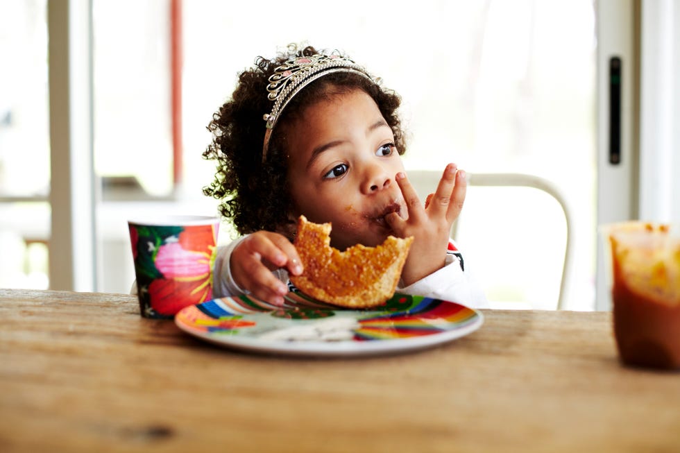 Mixed race girl eating lunch at table