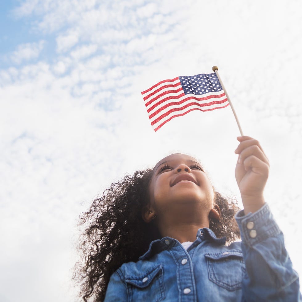 mixed race girl holding united states flag outdoors