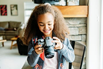 mixed race girl using camera in living room