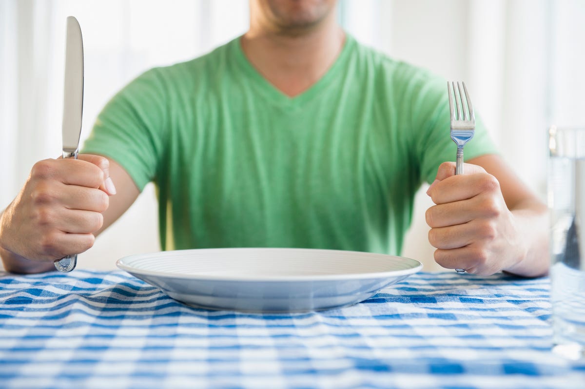 https://hips.hearstapps.com/hmg-prod/images/mixed-race-man-holding-fork-and-knife-at-table-royalty-free-image-1669278954.jpg?crop=0.88722xw:1xh;center,top&resize=1200:*