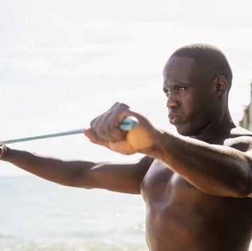 mixed race man using resistance band on beach