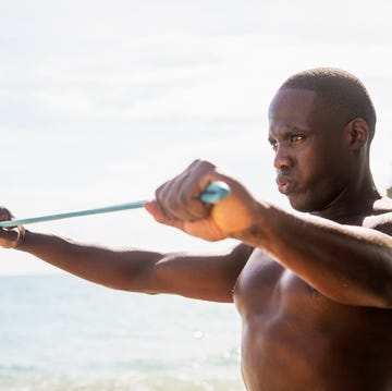 mixed race man using resistance band on beach