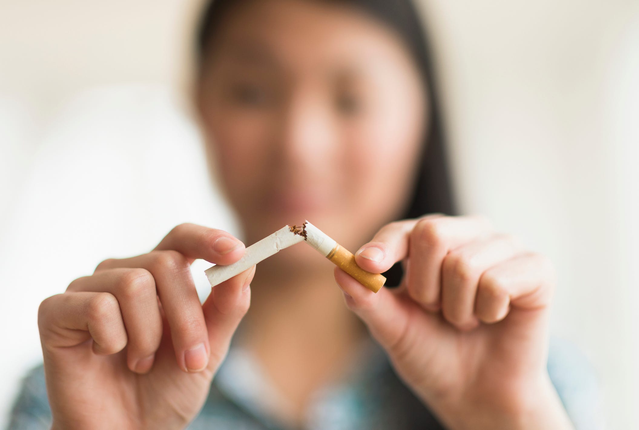 mixed race teenage girl breaking cigarette in half