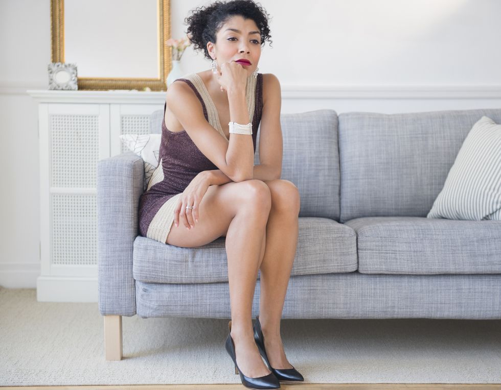 mixed race woman in cocktail dress sitting on sofa