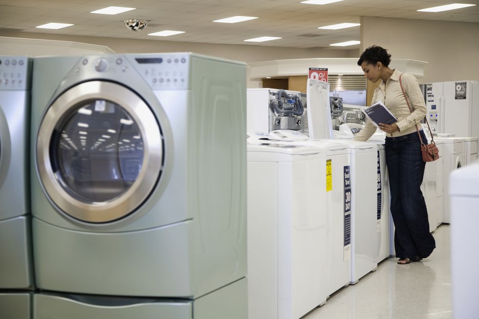 mixed race woman looking at washing machines in showroom