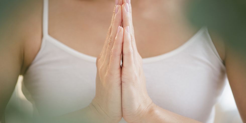 mixed race woman meditating with clasped hands