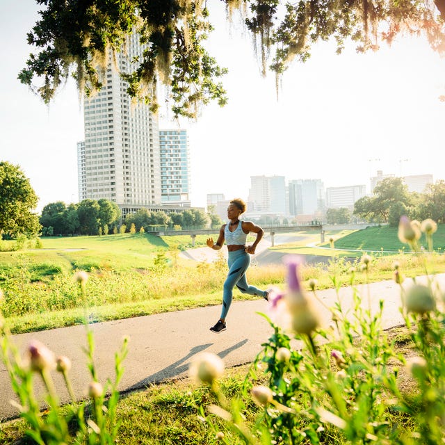 Mixed Race woman running on path in park beyond wildflowers