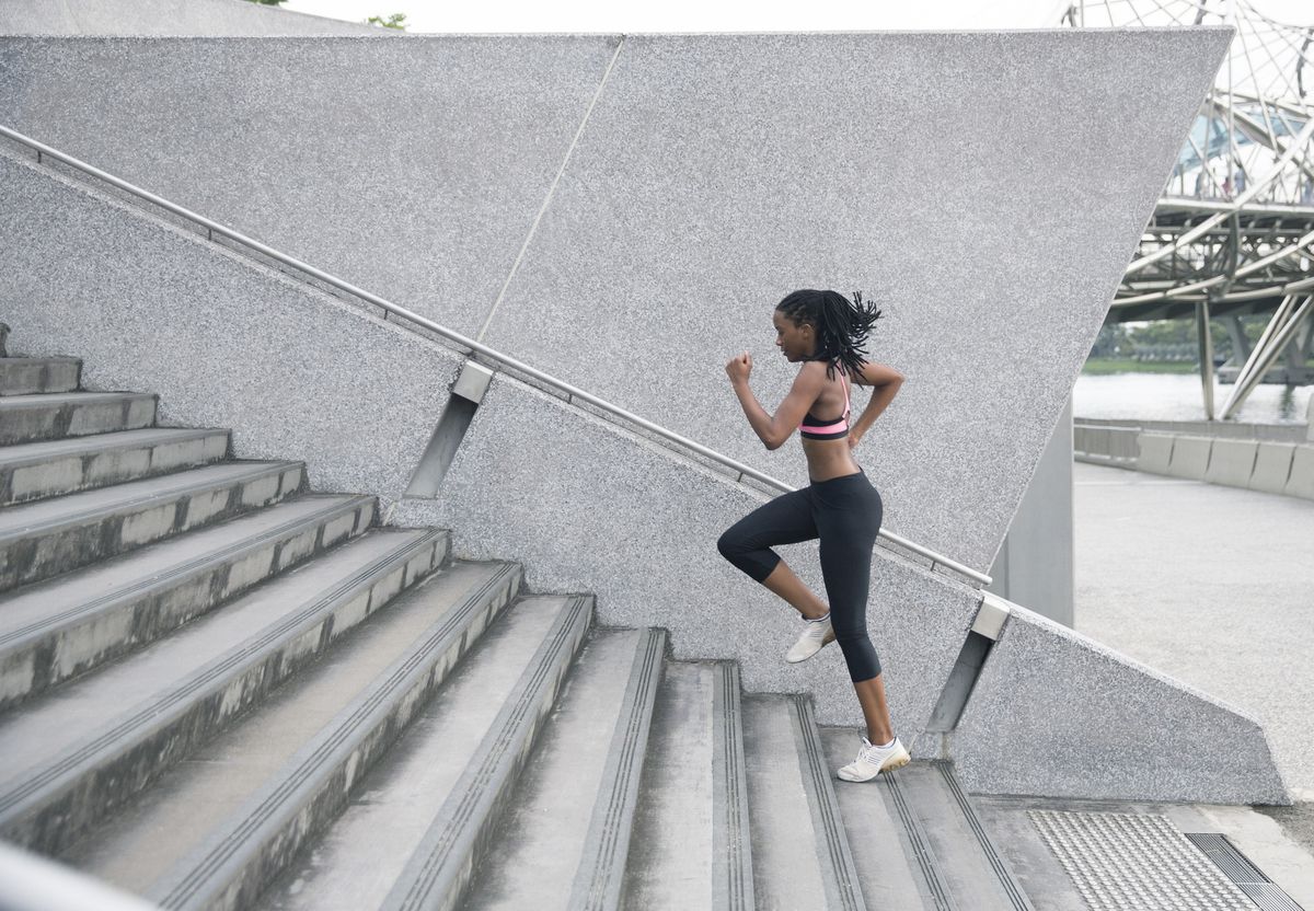 Mixed Race woman running up urban staircase