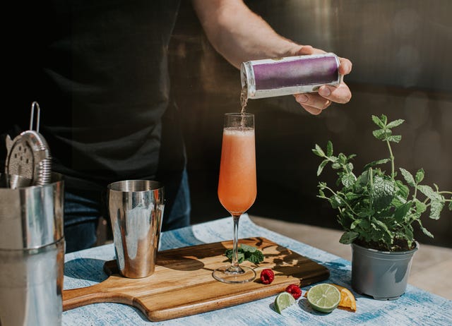a mixologist creates a delicious blended drink, topping it off with a carbonated juice from a can