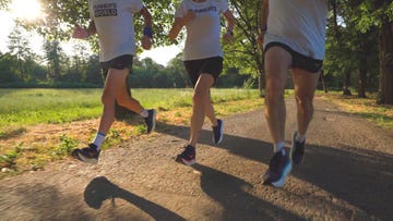 group of three runners in motion on a gravel path during daytime