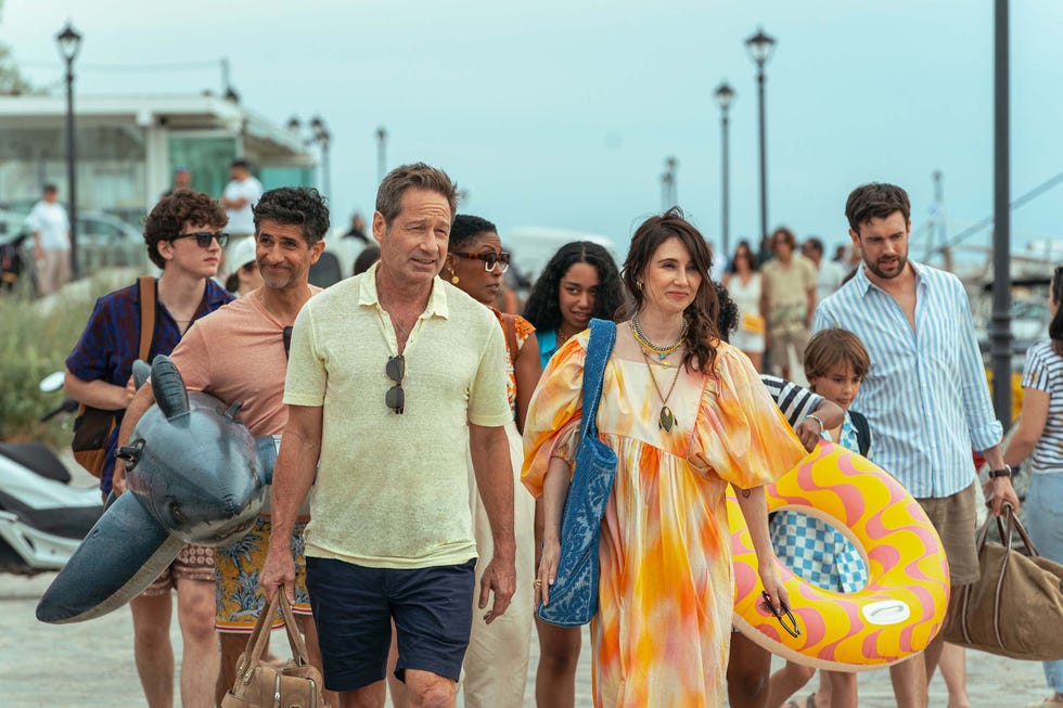 group of people walking along a seaside promenade some carrying beach inflatables