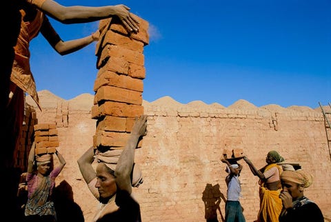 Jodi Cobb maakte voor een verhaal in National Geographic fotos van slechts enkele van de 27 miljoen mensen die wereldwijd slachtoffer zijn van slavenhandel in de 21e eeuw De meesten worden uitgebuit om te werken zoals dit gezin Ze stapelen en sjouwen stenen om hun lening af te betalen aan de eigenaren van een steenoven in het zuidoosten van India Door hoge rentetarieven en gerommel met de boekhouding zorgen de malafide bedrijfseigenaren ervoor dat de arbeiders hun schulden nooit kunnen afbetalen Die dragen ze vervolgens over op hun kinderen