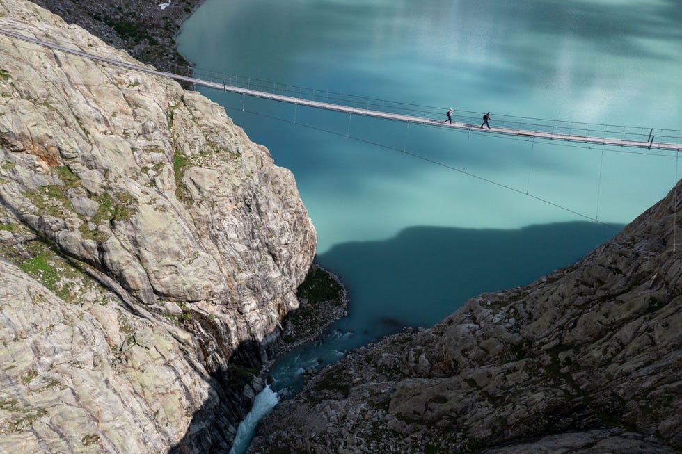Waar toeristen nu tientallen meters boven een kolkende smeltwaterrivier over een voetgangersbrug lopen liepen ze ooit over de tong van de Zwitserse Triftgletscher Het meer is pas in deze eeuw ontstaan en de brug werd in 2004 gebouwd Een energiebedrijf wil hier een stuwdam aanleggen