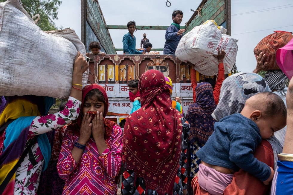 Lucknow, India LUCKNOW INDIAMigranten klimmen op een vrachtwagen die hen naar hun dorp in de buitenwijken van de metropool Lucknow India zal brengen 6 mei 2020 Toen de Indiase regering op 24 maart een nationale lockdown afkondigde verbood ze haar burgers om nog langer te reizen en op de plek te blijven waar ze op dat moment verbleven Maar daardoor kwam de voedselvoorziening voor de enorme migrantenbevolking die dagelijks vanuit omliggende dorpen naar de stad trekt in gevaar Na verdere beraadslagingen en de invoering van nieuwe veiligheidsmaatregelen slaagden de deelstaatregeringen erin de migrantenbevolking met speciale treinen naar hun dorpen terug te brengen