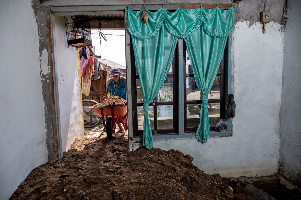 In het regentschap Demak in CentraalJava is het leven niet eenvoudig Nadat het dorp Purwosari in 2020 voor het eerst bij hoogwater onder water kwam te staan gebruikte Turadi aarde om zijn vloer op te hogen De bodem langs de kust daalt hier met tien centimeter per jaar mede als gevolg van het oppompen van grondwater