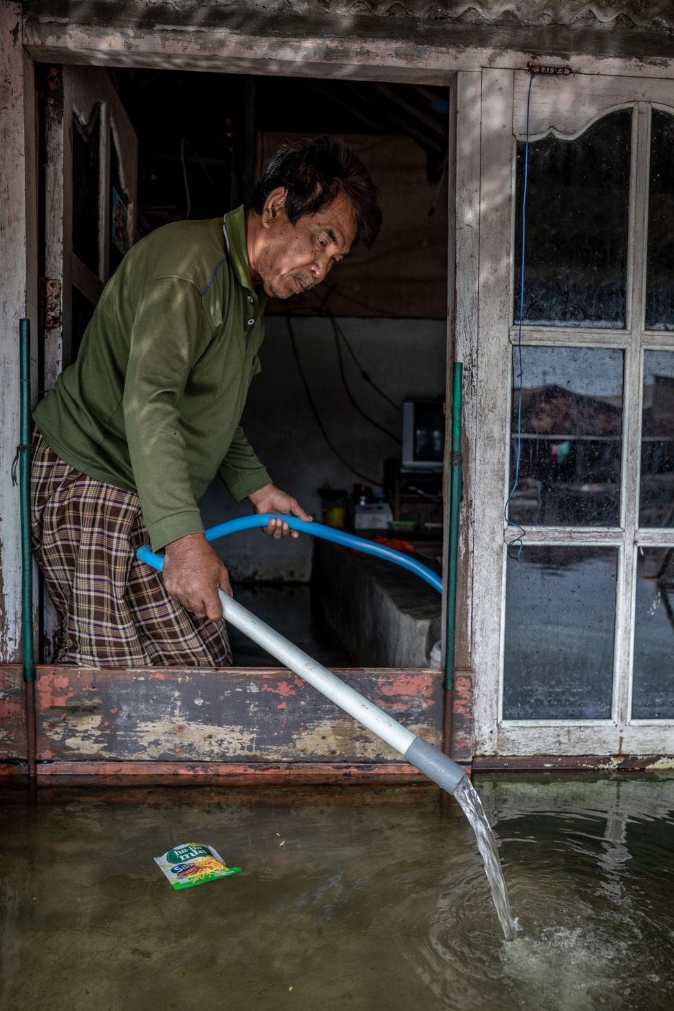 In het dorp Sriwulan pompt Maskuri water uit zijn huis Hij heeft zijn vloer al driemaal met aarde verhoogd en kan zich een volgende ophoging niet veroorloven