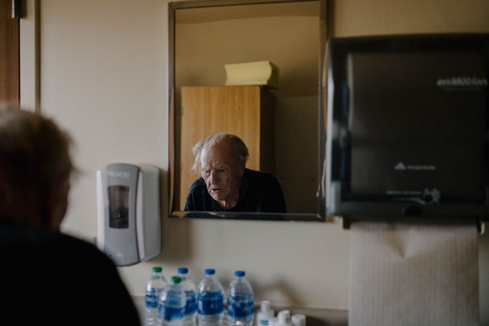 In zijn kamer in het verpleeghuis voor langdurige zorg vult John Olinger een 95jarige veteraan uit Tweede Wereldoorlog zijn waterfles bij Ik heb niet de vrijheid om naar buiten te gaan zegt hij Soms kan ik moeilijk ademhalen  ik denk dat het de spanning is Hij voelde zich eenzaam totdat hij de medebewoners van de rokersclub op de buitenveranda leerde kennen