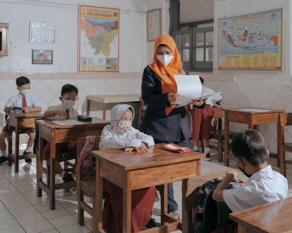 Jakarta, Indonesia JAKARTA INDONESINa lange tijd krijgen leerlingen weer persoonlijk les op de Lagere School Nr 1 in Jakarta Indonesi In de herfst van 2021 konden in de hele stad ruim zeshonderd scholen hun deuren weer openen voor persoonlijke lessen drie dagen in de week en onder strikte voorwaarden De scholen mogen niet te veel leerlingen tegelijk toelaten zodat de helft van de leerlingen van elke klas thuis wordt onderwezen via een videoverbinding De Indonesische minister van Onderwijs Nadiem Makarim maakte zich hard voor een terugkeer naar gewone lessen In het parlement zei hij dat de COVID19lockdowns leerachterstanden hebben veroorzaakt die permanente gevolgen hebben