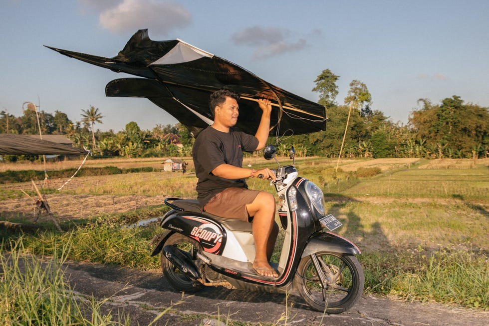 Agus Susandi Partayana vertrekt op de scooter met zijn bebean een visvormige vlieger uit het dorp Tunjuk
