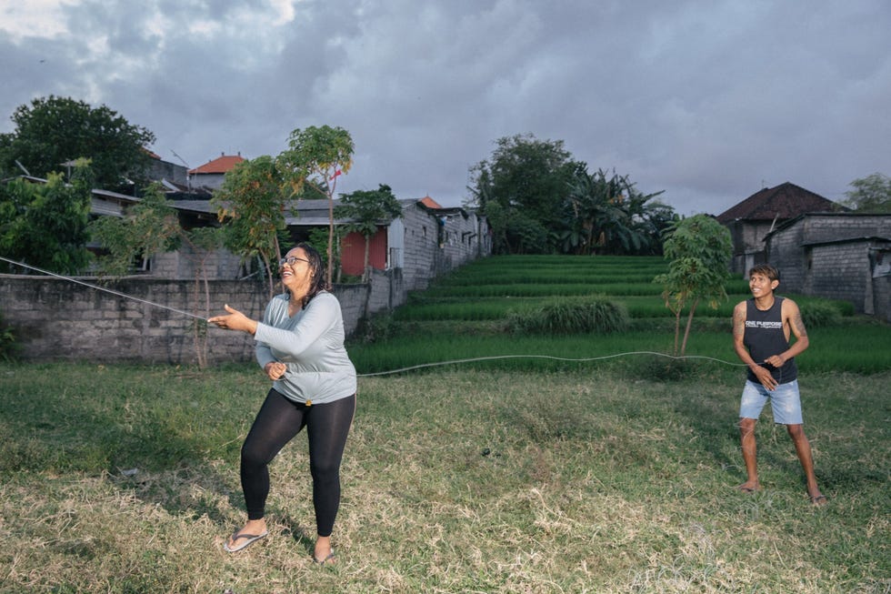 Wayan Sunariasia is samen met haar broer aan het vliegeren in het dorp Padang Sambian Zij is ook lid van Srikandi een vliegercollectief voor vrouwen