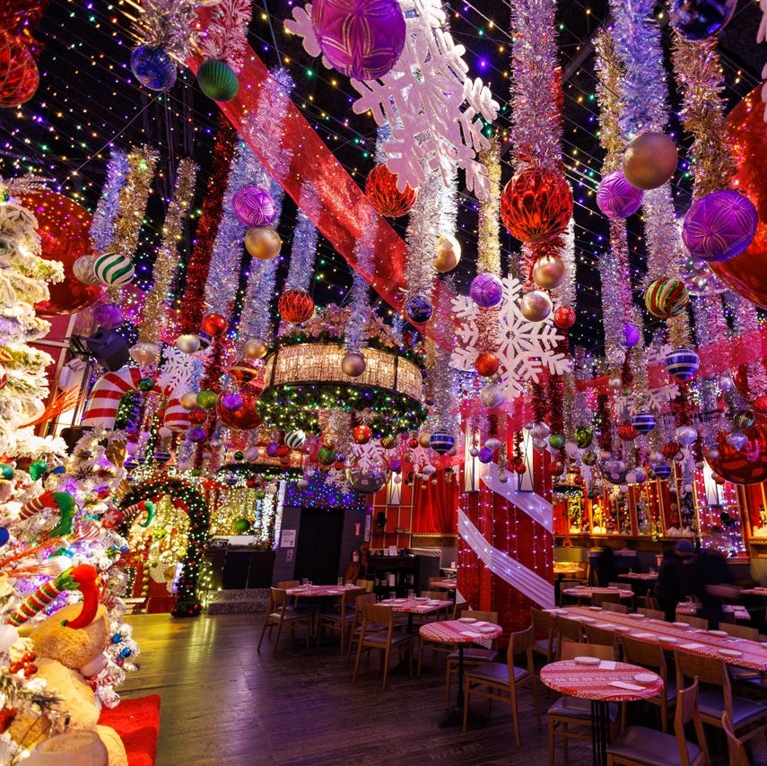 a room with tables and chairs with balloons from the ceiling