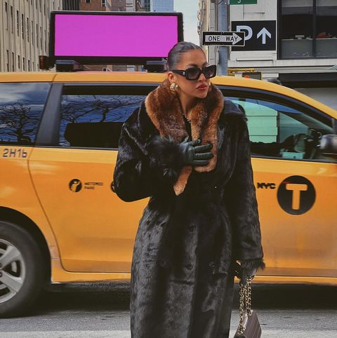 a person wearing a fur coat and sunglasses holding a camera