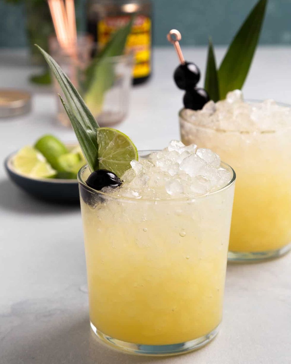 pineapple ginger beer mocktail in short glasses with crushed ice cherries and limes