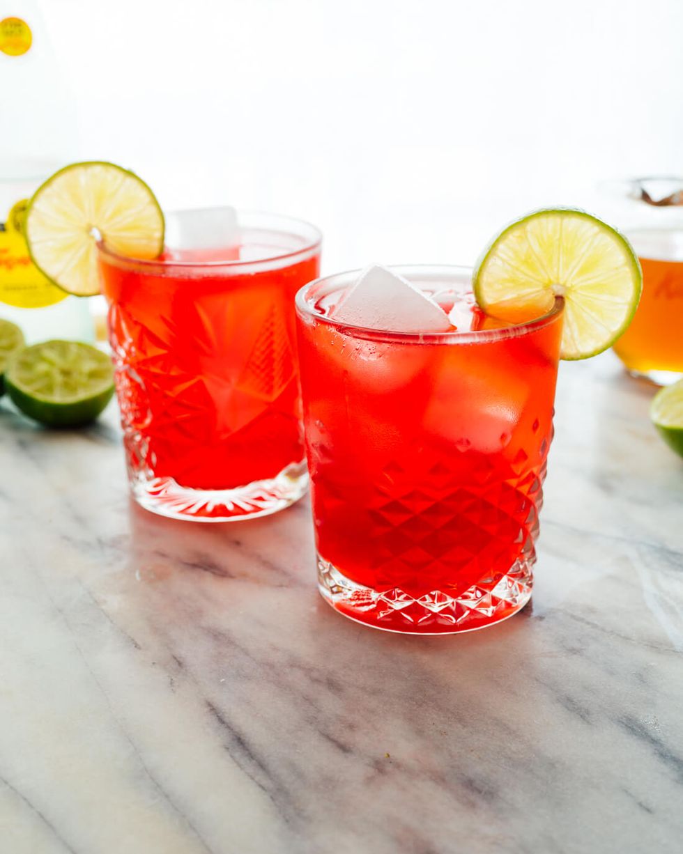 sparkling hibiscus mocktail in short glass with lime slice on marble