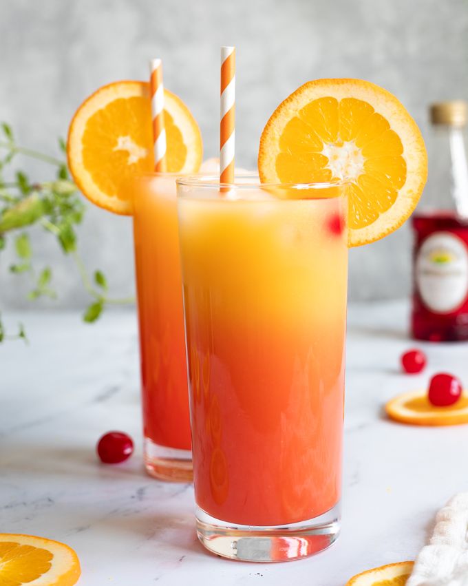 tequila sunrise mocktail in glass with orange slice and cherries