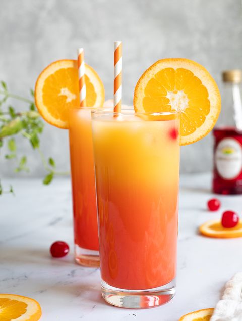 tequila sunrise mocktail in glass with orange slice and cherries