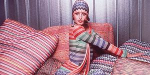 portrait of a model wearing a colorful outfit designed by missoni while posing on pillows covered in missoni fabric the outfit consists of a herringbone weave head scarf and maxi skirt and a striped top   photo by hulton archivegetty images
