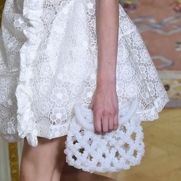 a model carrying a beaded white clutch on the simone rocha runway