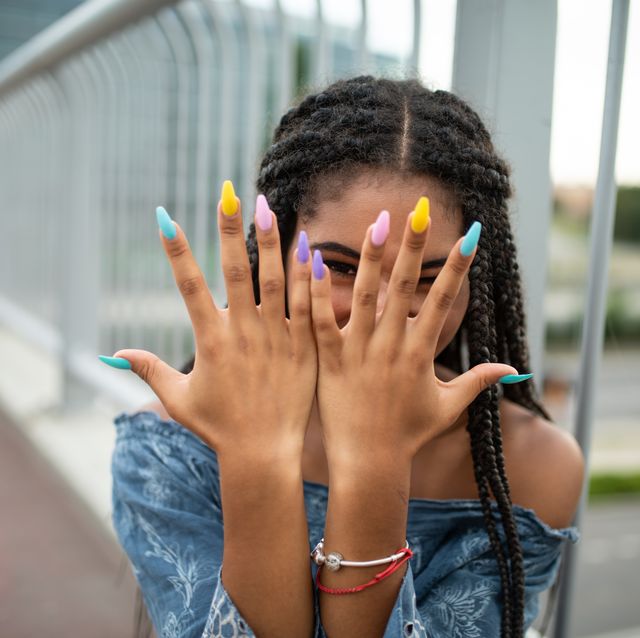 model on city bridge posing with colorful nails