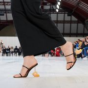 a model walks the loewe runway in a pair of strappy sandals to illustrate a roundup of the top spring 2022 shoe trends