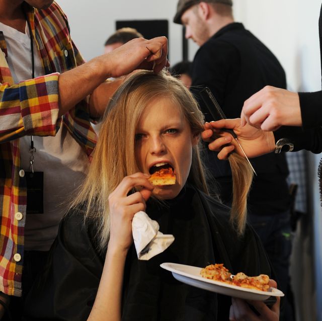 a model takes a bite of pizza while she