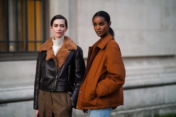 two models in fall jackets stand on a street corner in paris