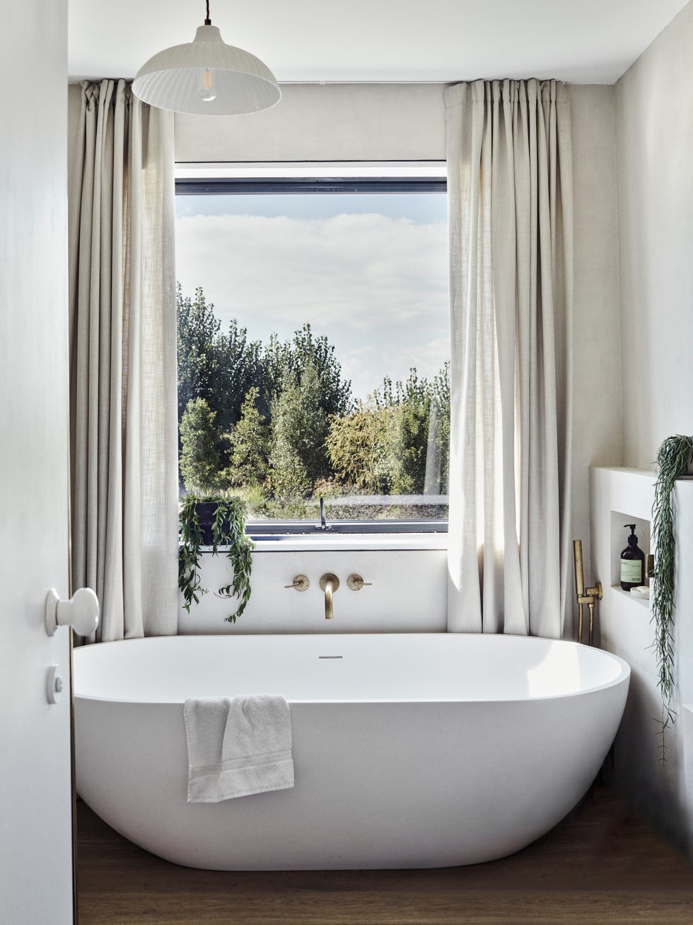 baño en tonos grises con bañera exenta y ventana al jardín