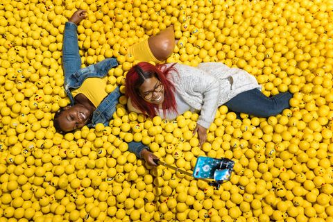Bezoekers liggen in een met emojis gevulde ballenbak in het Museum of Selfies in Los Angeles waar je fotos kunt maken tegen grappige achtergronden