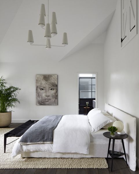 primary bedroom with soaring ceilings chandelier circa lighting bed gervasoni bench cb2 side table room board rug west elm art clients’ own 19th century carriage house in montclair nj interior design elaine santos designarchitect windigo architecture minimal and modern accents