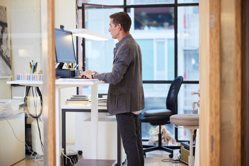 modern business office with a male employee standing in front of pc at a flexible workstation