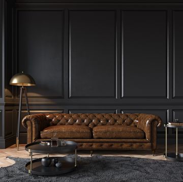 modern classic black interior with capitone brown leather chester sofa, floor lamp, coffee table, carpet, wood floor, mouldings 3d render interior mock up