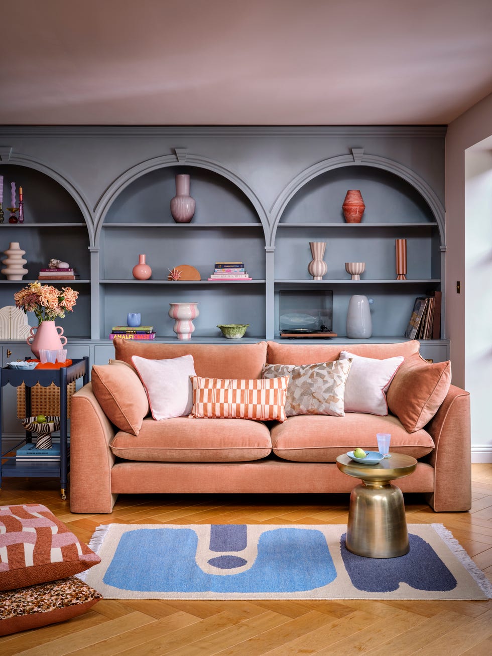living room featuring a sofa decorative pillows and shelves with vases and books