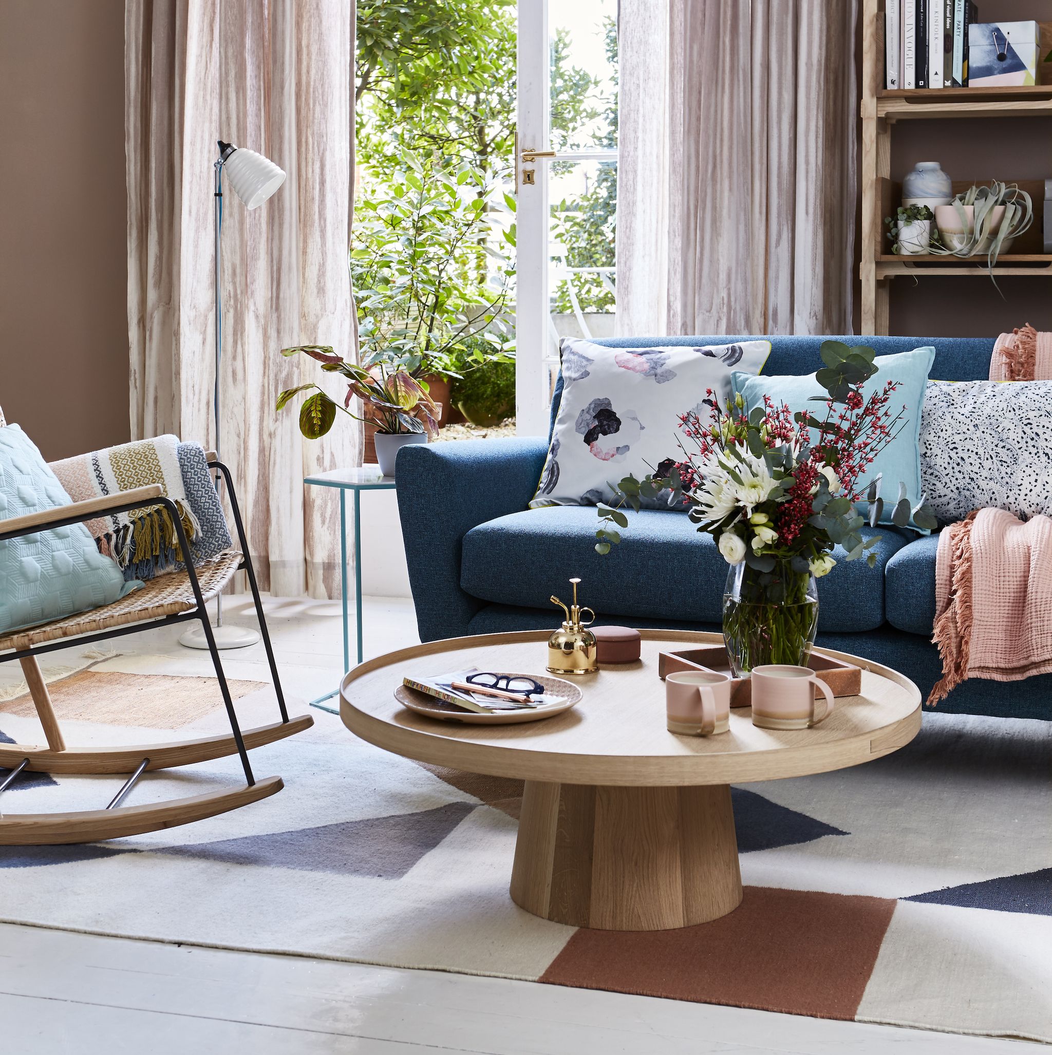 interior shot of a sitting room sofa and coffee tableliving room team a mid century style sofa with a pared back circularcoffee table for elegant simplicity lightweight full length curtains in aneutral colour bring softness and an airy feel to the room